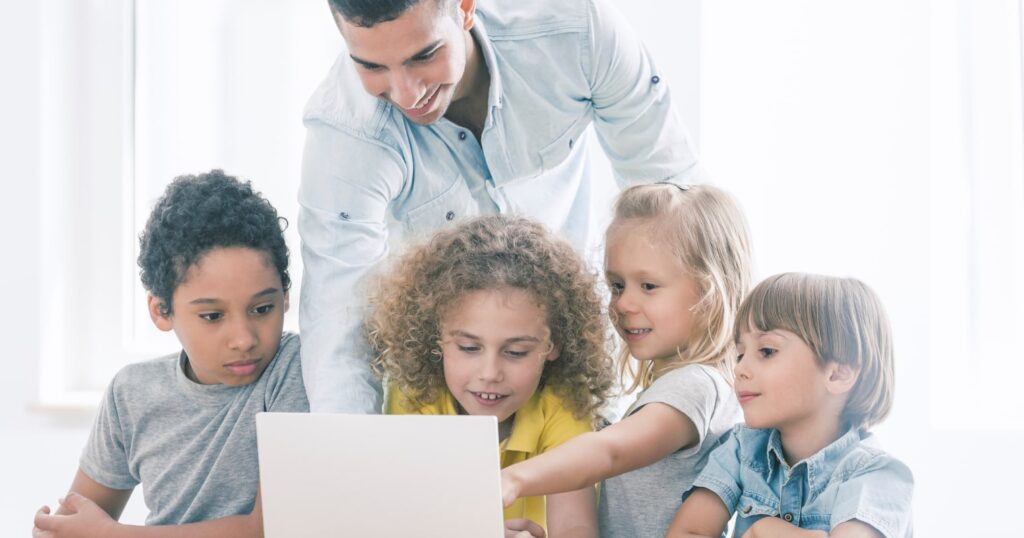 A képen egy apa és a gyerekek nézik a laptopot.