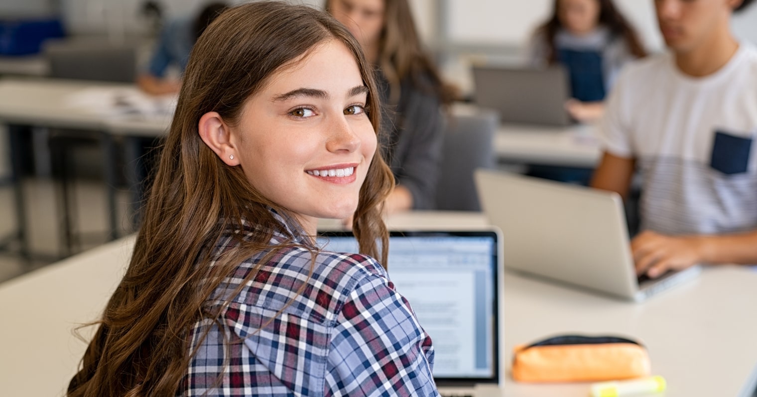 kompetenciamérés - diáklány mosolyog a laptop előtt