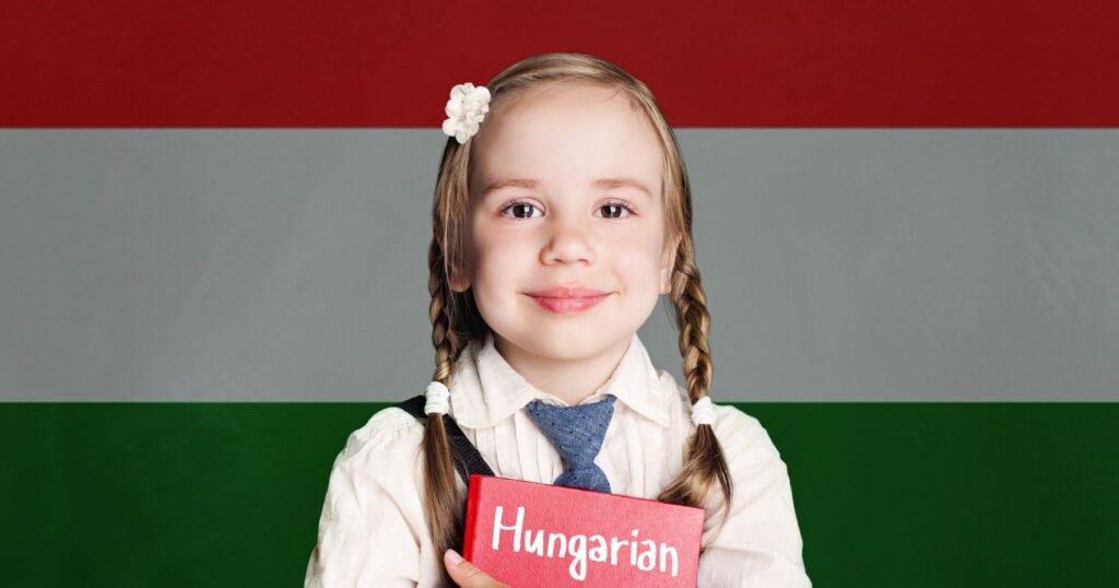 A magyar zászló előtt egy kislány áll, kezében a "magyar" feliratú könyv