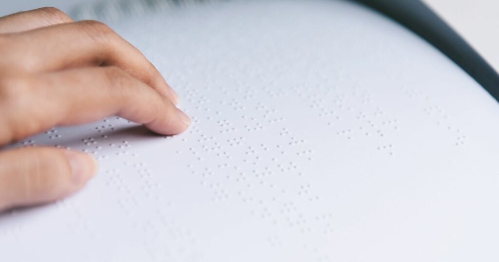 A képen Braille-írást olvasnak kézzel