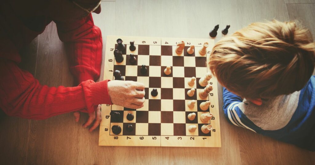 A képen egy sakk tábla látható felülről, egy felnőtt és egy gyerek játszik