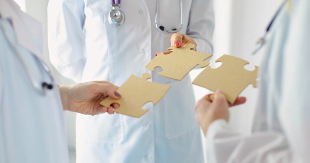 A képen orvosok láthatók, hárman tartanak egymáshoz illő puzzle darabokat