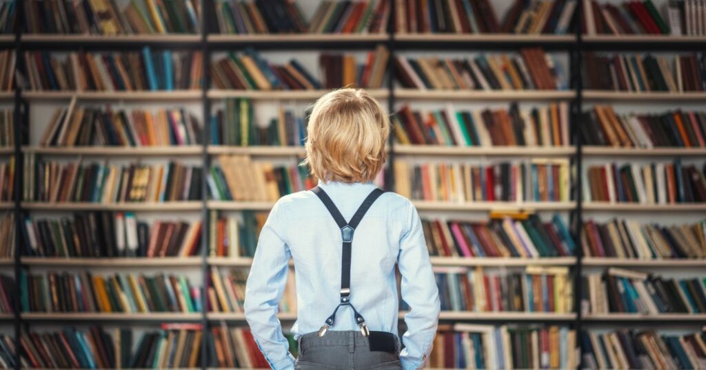 Egy kisfiú áll a könyvtári polc előtt