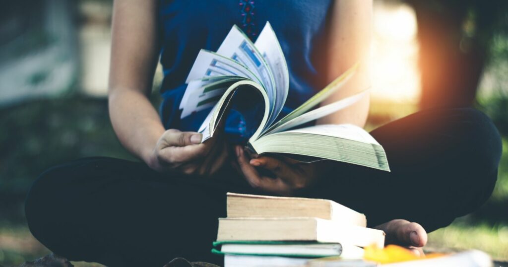 A képen egy nő teste látható, a kezében tartott könyvet lapozza