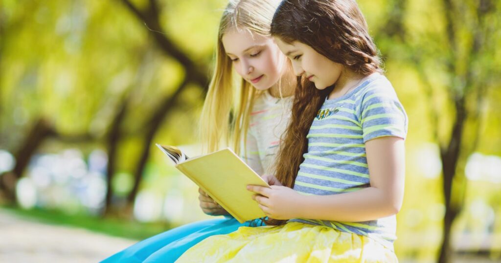 A képen két kislány egy könyvet olvas