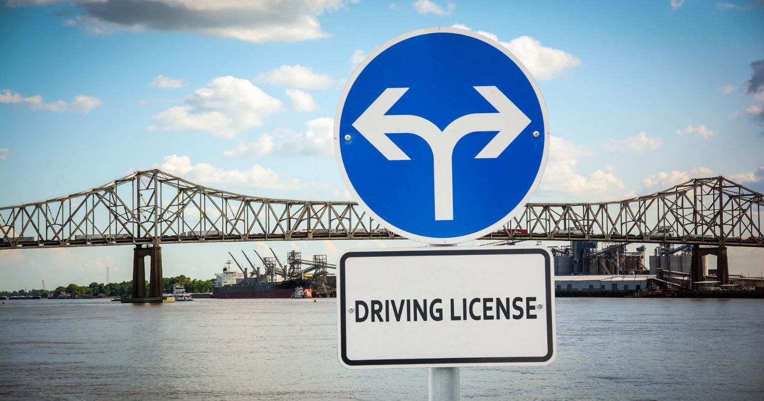 A képen egy útjelző táblán látható két nyíl, és alatta a jogosítvány szó olvasható angol nyelven