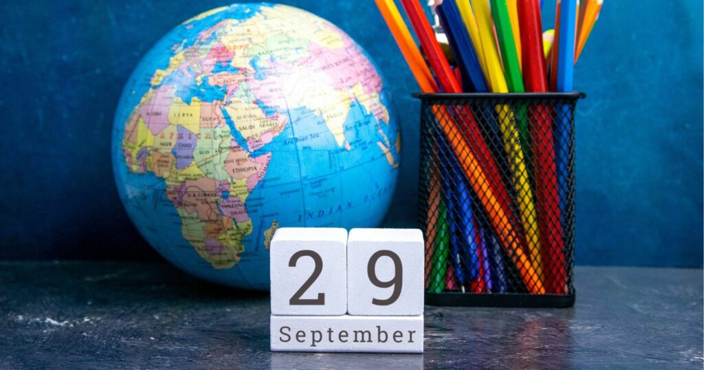 Egy földgömb és sok színes ceruza mellett egy fa naptáron a szeptember 29-i dátum látható