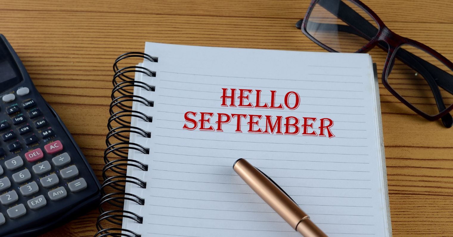 Egy noteszen egy toll és egy számológép mellett a hello szeptember felirat látható