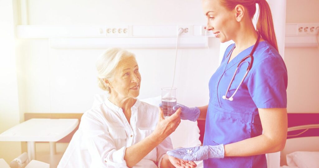 Egy idős nő vizet kap egy ápolótól