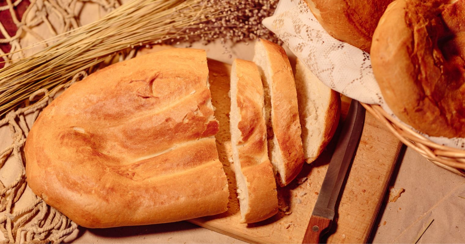 A képen felülnézetből egy vekni kenyér látható, egy marék búzakalász, és néhány másik kenyérből is részletek