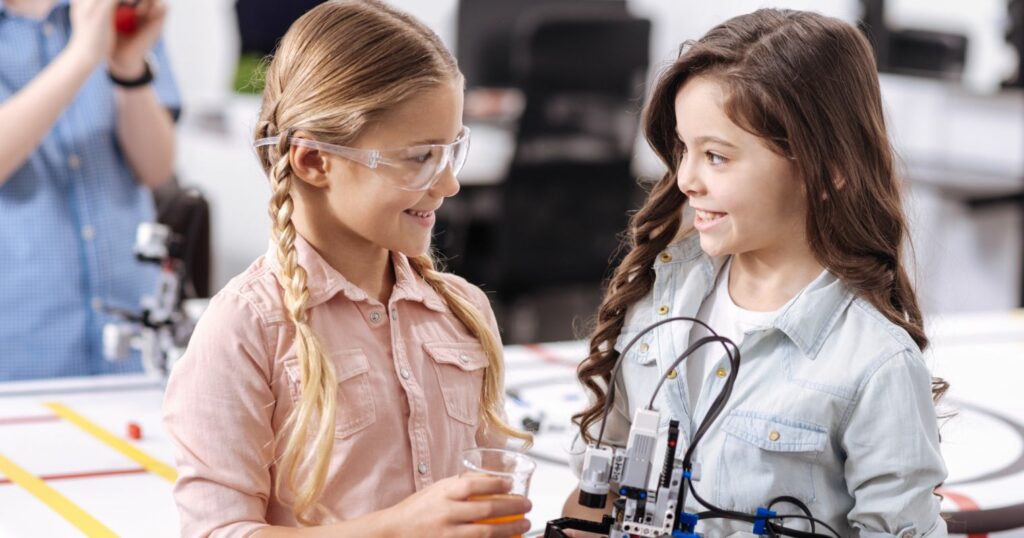Két kislány látható a képen, akiknek a kezében mini robot van