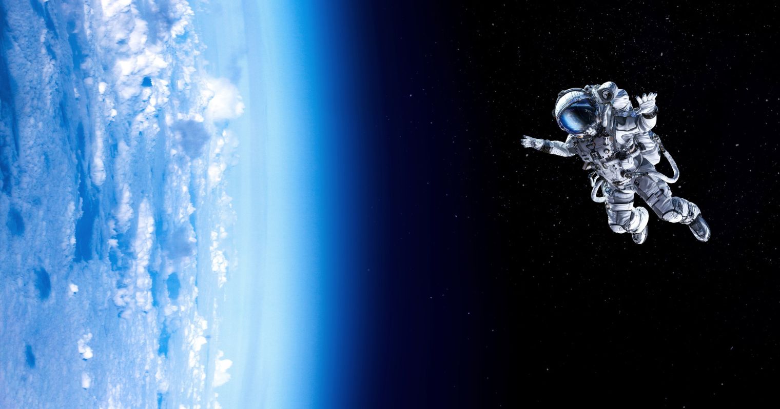 A képen egy asztronauta lebeg az űrben, a kép bal oldalán a Föld és a légkör egy része látható