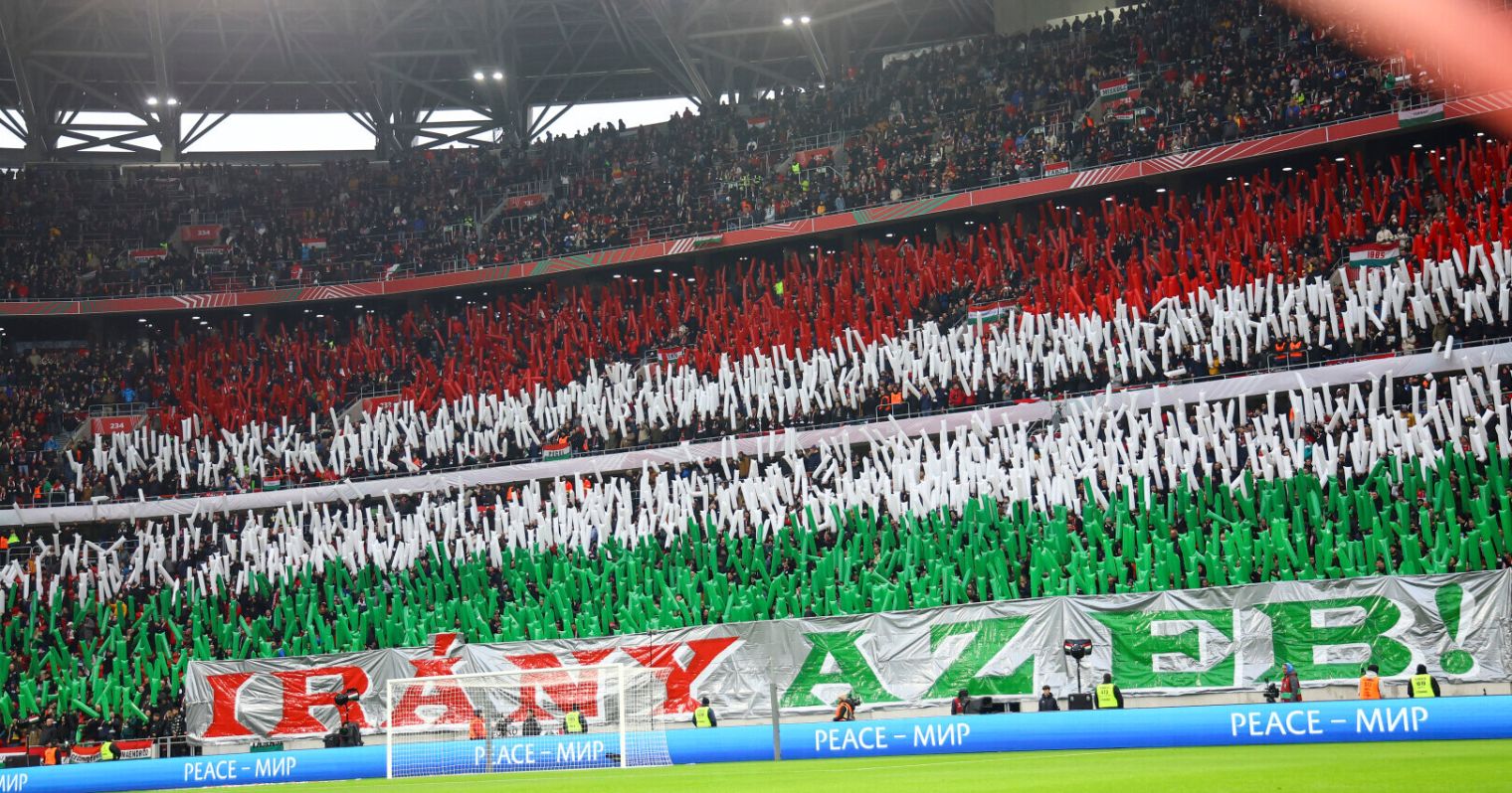 Magyarország-Montenegró meccs eleji szorkolói koreográfia, elöl "irány az eb" felirat, mögötte a feltartott rudakból magyar zászló.