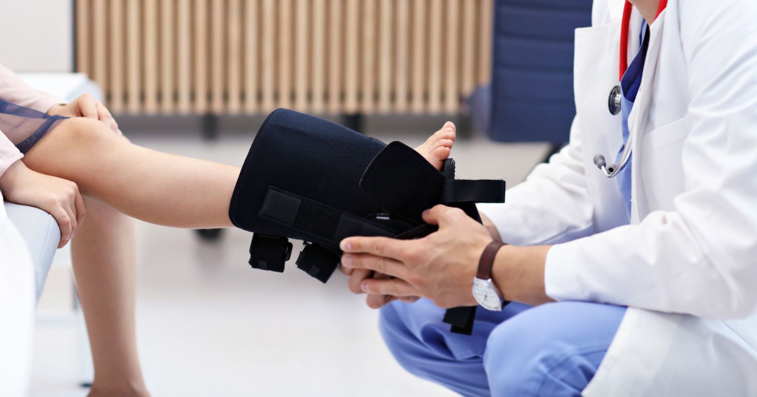 Ortopédiai műszerész tesz fel egy rögzítőt egy kislány lábára.