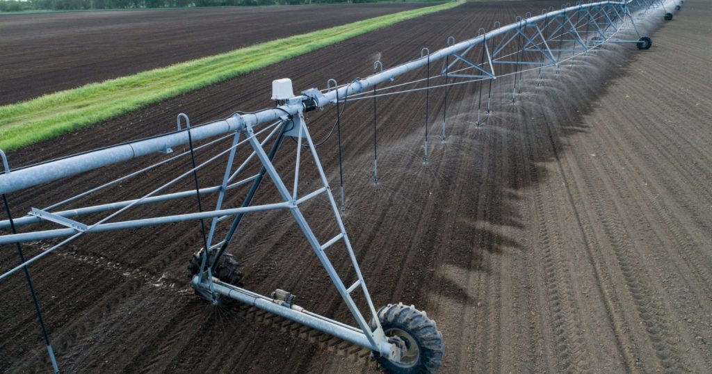 Mezőgazdasági automatizált öntözőrendszer megy egy földterület felett és öntözi a földet.