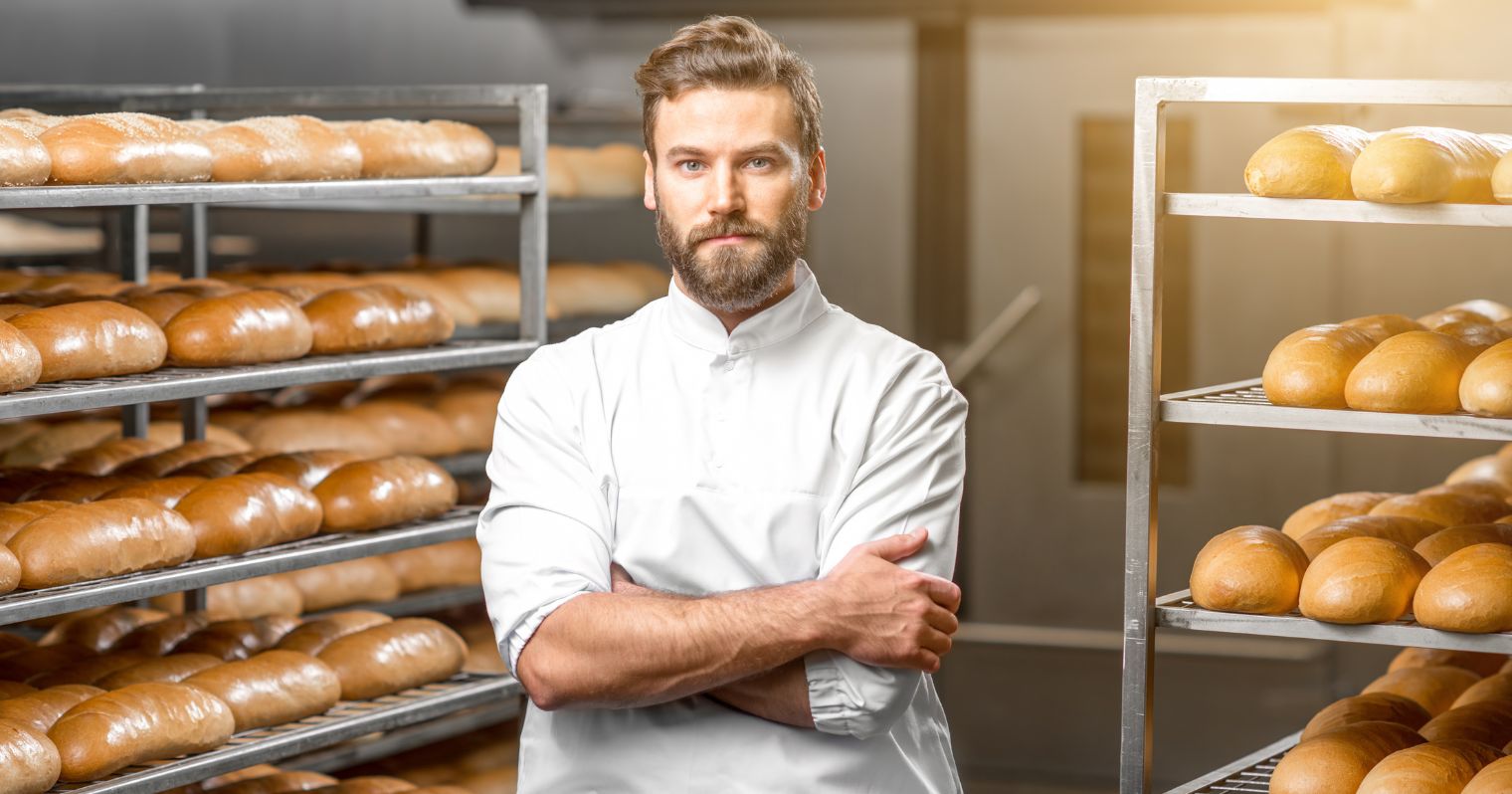 A képen a sütő- és cukrászipari technikus látható az elkészült kenyerek mellett.