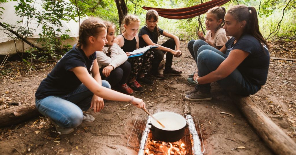Nomád tábor, a cserkészet fontos része, cserkész őrs ül az erdőben és szabad tűzön főznek.